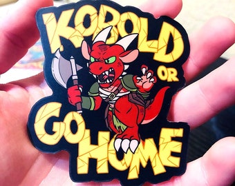 May include: A black and yellow sticker featuring a red, green-eyed kobold wielding an axe. The sticker reads "Kobold or Go Home".