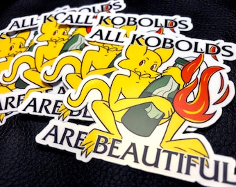 May include: A set of stickers featuring a yellow cartoon kobold holding a bottle of liquid with a lit wick. The stickers have the text "All Kobolds Are Beautiful" and "All Kobolds Are Beautiful".