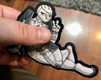 May include: A white and black sticker of a cartoon robot character with red eyes, wearing a black and white outfit, and making a peace sign with one hand.