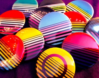 May include: A collection of colourful striped round buttons with black and white stripes. The buttons are arranged in a circle on a purple surface.