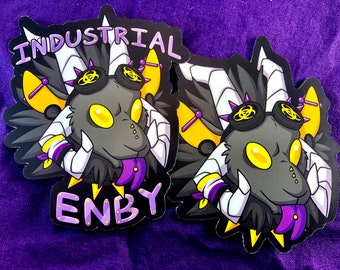 May include: Two black and white stickers featuring a cartoon dragon wearing goggles and a purple tongue. The text "INDUSTRIAL ENBY" is on the stickers.