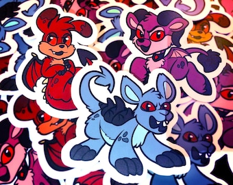 May include: Three colourful cartoon stickers featuring a red, blue and purple creature with wings and horns. Each sticker has a white outline and red eyes.