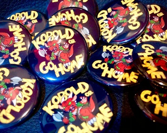May include: A collection of round, black and yellow buttons featuring a cartoon kobold character wielding an axe. The buttons read "Kobold or Go Home".