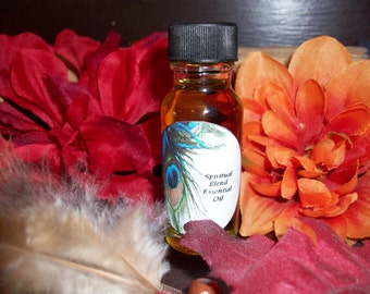 May include: A small glass bottle with a black cap filled with a golden liquid. The bottle has a white label with a peacock feather design and the text "Spiritual Blend Essential Oil".