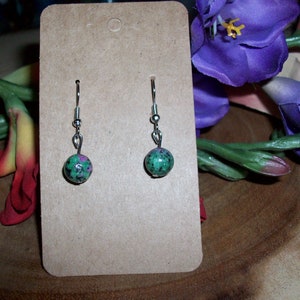 May include: A pair of silver dangle earrings with green and pink gemstone beads.