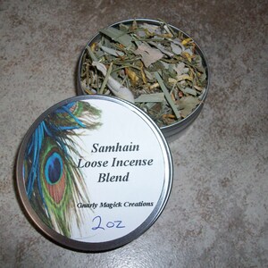 May include: A silver tin with a white label that reads "Samhain Loose Incense Blend" and "Gnarly Magick Creations" with a peacock feather design. The tin contains a blend of dried herbs and is labeled 2 oz.