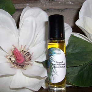 May include: A glass roller bottle with a black cap and a white label that reads "Empath Relief Blend Essential Oil". The label has a peacock feather design.
