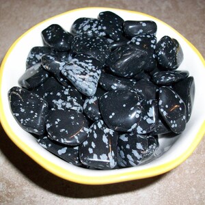 May include: A bowl filled with black and white snowflake obsidian tumbled stones. The stones are smooth and polished, with a speckled pattern.