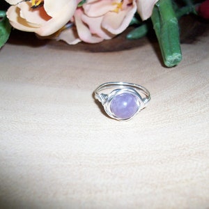 May include: A silver wire wrapped ring with a light purple gemstone.