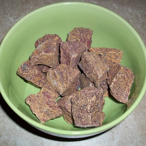 May include: A green bowl filled with brown and gold patterned rocks. The rocks are irregularly shaped and have a rough texture.