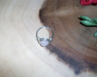 May include: A silver wire wrapped ring with a pale pink gemstone.