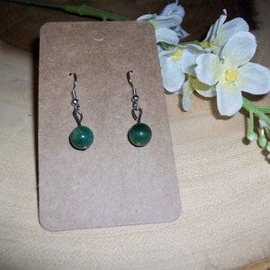 May include: A pair of silver dangle earrings with green gemstone beads.