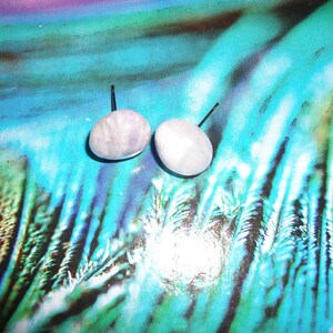May include: A pair of lavender and white gemstone earrings with silver posts. The earrings are round and have a smooth, polished finish.