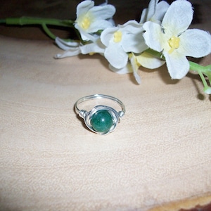 May include: A silver wire wrapped ring with a dark green gemstone.