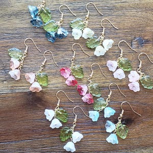 May include: A set of 10 pairs of earrings featuring delicate flower and leaf designs. Each pair features a different color combination of pastel blue, green, white, pink, and red.