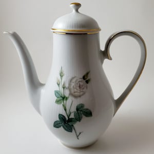 May include: White porcelain coffee pot with a gold trim and a single white rose with green leaves painted on the side.