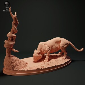 May include: A detailed, unpainted, beige resin figurine of a crouching lioness with a snake wrapped around a tree trunk in the background. The figurine is on a textured oval base.