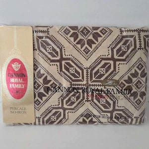 May include: A packaged set of Cannon Royal Family percale no-iron sheets. The sheets are patterned with a geometric design in shades of brown and beige. The packaging includes the brand name and product details.