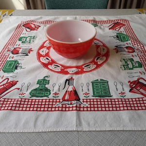 May include: A white tablecloth with a red and white checkered border features a repeating pattern of kitchenware, including coffee pots, teacups, and stoves. A red mixing bowl sits in the center of the tablecloth.