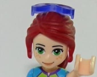 Puede incluir: Una minifigura Lego de una niña con cabello rojo, que lleva una camisa verde con un diseño de rayo, pantalones cortos morados y zapatos azules. Lleva una diadema azul.