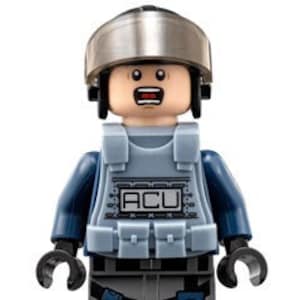Pode incluir: Uma minifigura Lego azul e cinza vestindo um capacete e um colete com as letras "ACU" impressas. A minifigura tem uma expressão de surpresa no rosto.