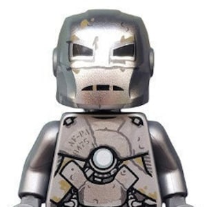 Pode incluir: Uma minifigura Lego de Iron Man em prata e cinza com um visual metálico desgastado. A figura tem um torso detalhado com uma placa de peito prateada e um design cinza desgastado. A figura também tem um capacete prateado com uma viseira vermelha.