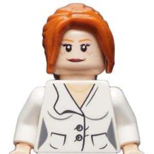 Peut inclure: Une figurine en plastique avec des cheveux orange vif, un teint clair et une veste blanche dotée de deux boutons noirs et d'accents gris sur les côtés. Le visage imprimé présente des yeux sombres, des sourcils arqués, des taches de rousseur.