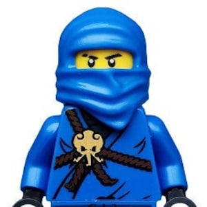 Może przedstawiać: Niebieska minifigurka Lego z czarnym wzorem czaszki i skrzyżowanych kości na klatce piersiowej, nosząca niebieską maskę ninja i niebiesko-czarny pasek.