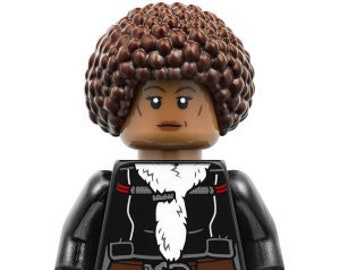 May include: A Lego minifigure of a woman with brown hair, wearing a black jacket with a white fur collar, a brown belt, and black pants.