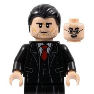 Può includere: Una minifigure Lego di un uomo che indossa un abito nero con una cravatta rossa. La minifigure ha una parrucca nera e un'espressione facciale di preoccupazione.