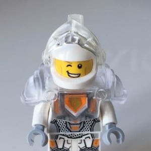 Peut inclure: Une figurine Lego blanche avec un casque transparent et une armure orange et grise. La figurine fait un clin d'œil et a une expression joyeuse.