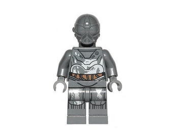 Può includere: Una minifigure Lego grigia con un elmetto grigio e un torso grigio e bianco. La minifigure ha una cintura grigia e gambe grigie.