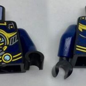 May include: A Lego minifigure torso in dark blue with black arms. The front features a yellow and gray design with a circular element and a blue gem. The back has a yellow arrow design.