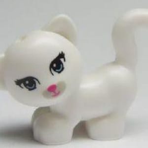 May include: A white plastic toy kitten with blue eyes, pink nose, and black eyelashes. The kitten is standing on all fours with its tail curled up.