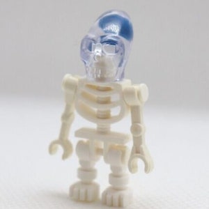 Pode incluir: Uma figura de esqueleto de plástico branco com um crânio de plástico azul translúcido. O esqueleto tem uma caixa torácica, braços, pernas e uma pélvis.
