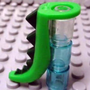 May include: Green plastic LEGO piece with a black dinosaur tail and a clear blue tube attached.