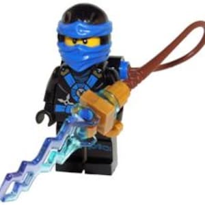 Może przedstawiać: Minifigurka Lego Ninjago w czarnym i niebieskim stroju, z niebieską opaską na głowie i żółtą twarzą. Figurka trzyma brązową i złotą broń z niebieską błyskawicą. Figurka stoi wyprostowana.