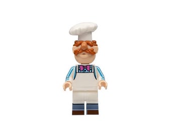 May include: A Lego figure of a chef wearing a white chef's hat, a white apron, and a pink bow tie. The chef has a large orange mustache and eyebrows. The figure has blue and white striped sleeves and blue pants.