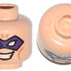 May include: Two light tan Lego minifigure heads. One head features a purple mask and a smiling mouth. The other head is viewed from the top, showing the hole for attachment to the body.