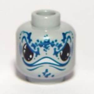 May include: A light gray Lego minifigure head with a detailed blue facial design. The design includes large, black eyes, a curved white mouth, and intricate blue patterns around the eyes and forehead.