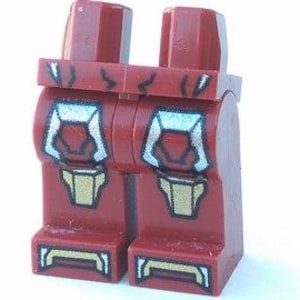 May include: A pair of Lego minifigure legs in a dark red color. The legs feature a printed design with white, gold, and black accents, depicting a stylized armored appearance. The design includes details on the knees and lower legs.