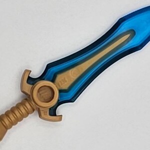 May include: A blue and gold plastic sword toy with a detailed design. The blade is translucent blue with a gold trim. The handle is gold with a textured grip.