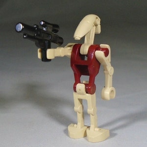 May include: A beige and red Lego Star Wars battle droid figure holding a black blaster.