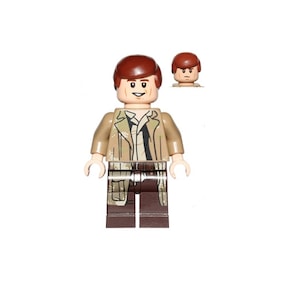 Könnte beinhalten: Eine Lego-Minifigur eines Mannes mit braunen Haaren, einer braunen Jacke, einem schwarzen Hemd, braunen Hosen und einem braunen Gürtel. Die Minifigur lächelt und hat einen hellbraunen Hautton.
