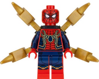 May include: A red and blue Lego minifigure of Spider-Man wearing a gold and blue suit with a spider logo on the chest. The figure has four gold arms with pointed ends.