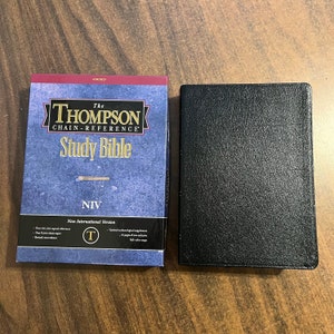 May include: A black leather-bound Thompson Chain-Reference Study Bible with the NIV (New International Version) printed on the cover. The cover also includes details about the Bible, such as over 100,000 topical references, over 8,000 chain topics, and updated archaeological supplements.