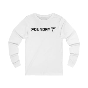 May include: White long-sleeve shirt with the word "FOUNDRY" printed in black across the chest. The shirt features a crew neck and a black graphic logo to the right of the word "FOUNDRY".