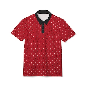 May include: Red polo shirt with a black collar and a white golf flag pattern. The shirt has short sleeves and a three-button placket. The golf flag pattern is repeated across the entire shirt.