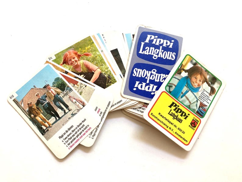 Op de afbeelding: Een verzameling vintage Pippi Langkous speelkaarten. De kaarten bevatten illustraties van Pippi en andere personages, met tekst in het Nederlands. De kaarten zijn gerangschikt op een wit oppervlak.