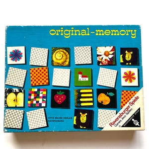 May include: A rectangular board game box titled original-memory with a bright blue background. The box features a grid of square tiles displaying various illustrations including a strawberry, a lion, an apple, a flower, and geometric patterns.